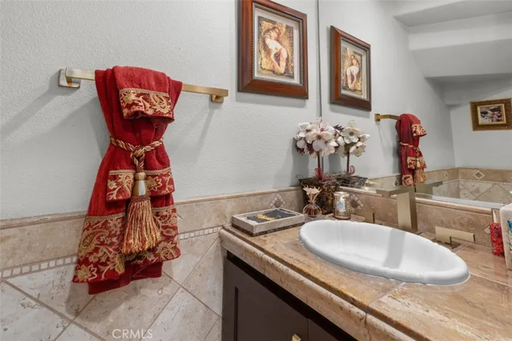 The powder bath impresses with a travertine tile surround, granite vanity countertop, and brushed gold hardware accents. Thoughtfully styled and elegantly finished, this guest bath reflects the same attention to detail found throughout the entire home.