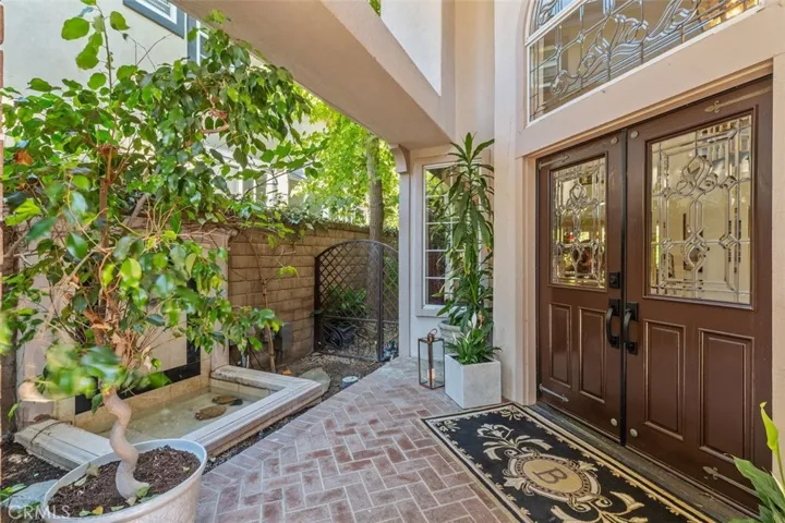 A private courtyard with custom brick paver walkway and serene fountain welcomes you home through dramatic double doors with leaded glass detailing.