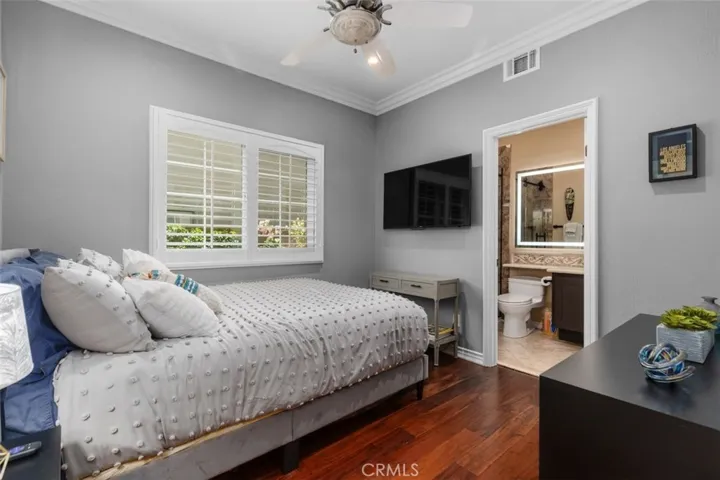 The main level bedroom with ensuite offers hardwood floors, crown molding, plantation shutters, a ceiling fan, and an updated private bath with lighted vanity mirror. This generously sized room with walk in closet is ideal for guests or multigenerational living and provides exceptional comfort and privacy.
