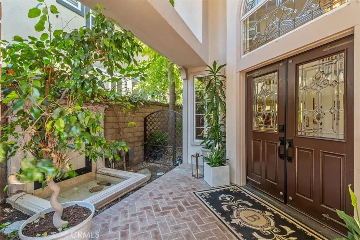 A private courtyard with custom brick paver walkway and serene fountain welcomes you home through dramatic double doors with leaded glass detailing.
