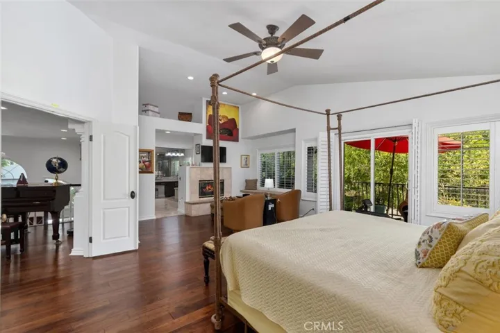 The luxurious primary suite offers warm hardwood floors, plantation shutters, a private balcony overlooking the lush slope and pool, and a two sided fireplace shared with the spa bath. The spacious layout includes a dedicated sitting area and direct access to the serene outdoor balcony.