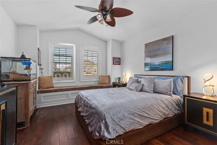 This bright and airy upper level bedroom features warm hardwood floors, vaulted ceiling, plantation shutters, a ceiling fan, and a charming built in window seat with storage below. A walk in closet and direct access to the Jack and Jill bath make this an especially desirable and functional space.