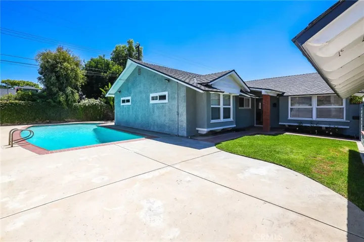 View of the sparkling pool and front entry of home.