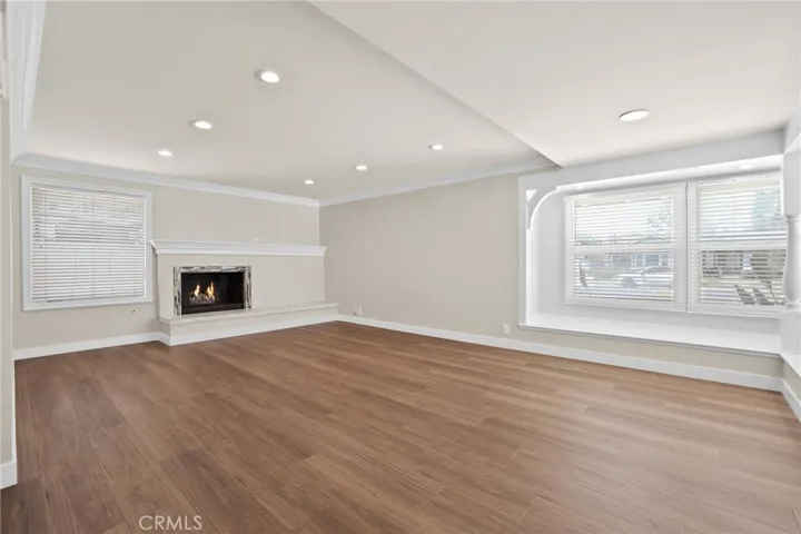 Living room has smooth ceilings, recessed lighting, large windows to let in natural sunlight and a gas fireplace with hearth and mantle.