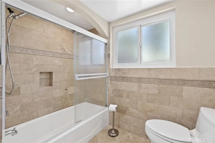 Primary bathroom - shower/tub with decorative stone tile,.