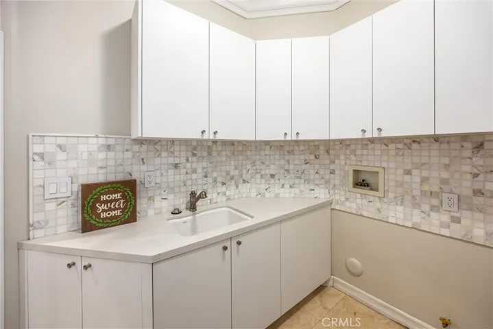 Convenient laundry room with a utility sink and plenty of cabinet storage