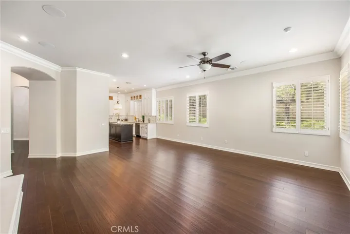 Expansive family room featuring a fireplace, custom built-in entertainment center, engineered wood flooring, and a seamless open flow to the gourmet kitchen