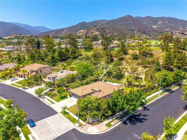 Aerial view showcasing the home's corner lot location, surrounding neighborhood, and scenic mountain backdrop