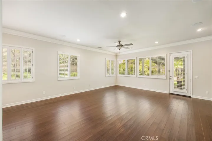 Expansive family room featuring crown molding, recessed lighting, plantation shutters, and direct access to the covered patio, creating a seamless connection between indoor and outdoor living