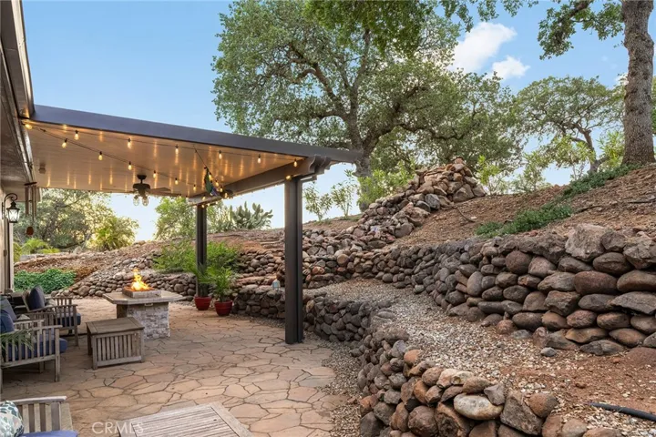 Luxurious outdoor living space with covered patio, built-in firepit and waterfall!