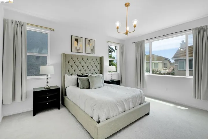 Bright interior featuring a contemporary gold-finish chandelier, multiple windows, and light-toned carpeting