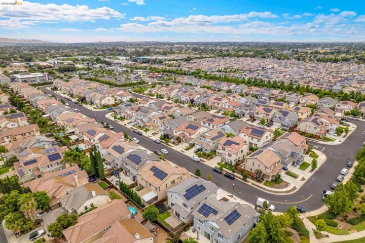 Aerial perspective showcasing a residential neighborhood with numerous homes featuring solar panel installations