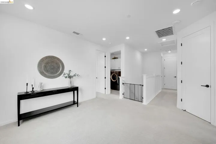 Upper-level landing featuring light-toned carpet flooring, recessed lighting, and white walls