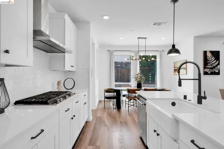 Modern kitchen featuring white shaker cabinetry, an integrated gas range with stainless steel hood, white subway tile backsplash, and wood-finish flooring