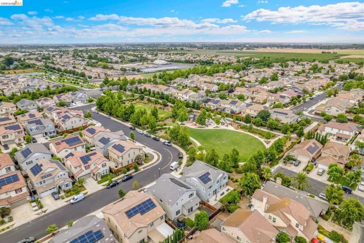 Expansive residential community featuring a central green space, numerous mature trees, and paved roadways