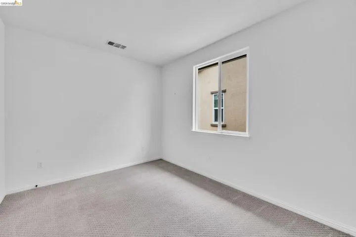 Room with light gray wall paint, a single window, and textured gray carpet