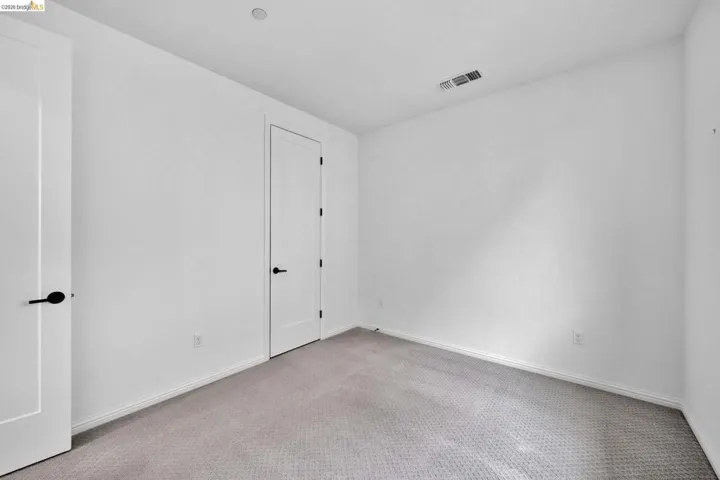 Neutral tone walls with white trim, gray patterned carpeting, and two paneled doors with matte black hardware