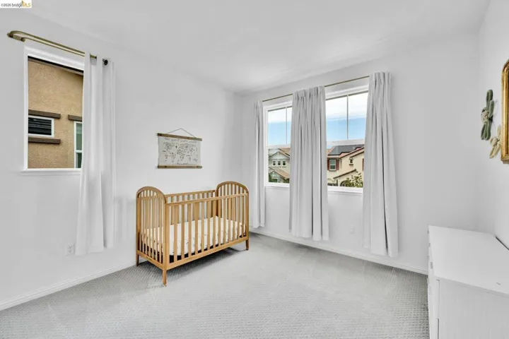 Light-filled room featuring multiple windows, white painted walls, and light-toned carpeting