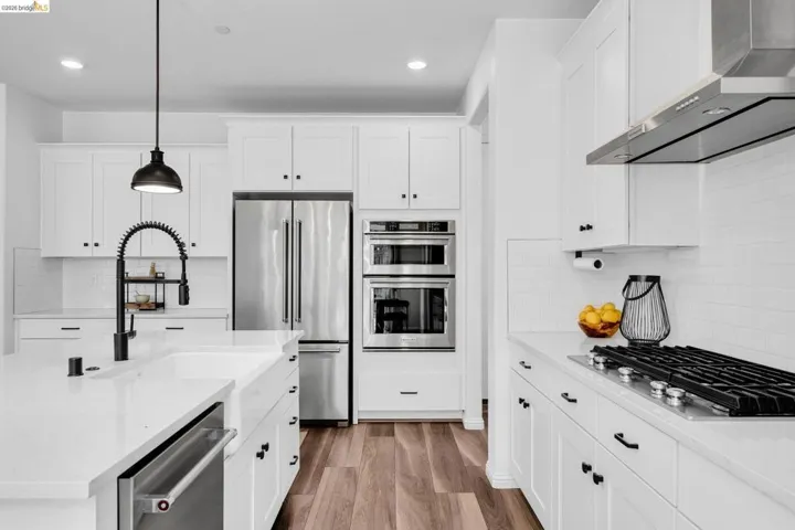 Modern kitchen featuring white cabinetry, stainless steel appliances, a gas range, and wood-finish flooring