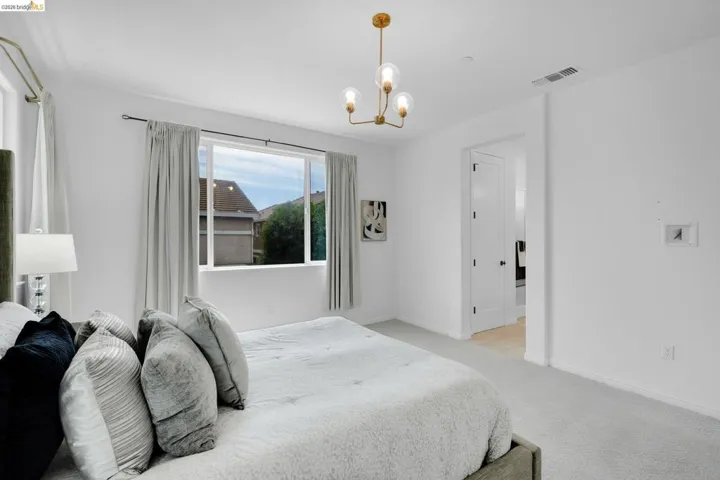 Bedroom featuring a white ceiling, light gray carpet, and a modern gold-finish chandelier with glass globes