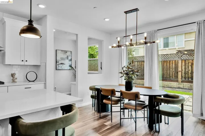 Open-concept kitchen and dining area featuring wood-finish flooring, white cabinetry, and recessed lighting
