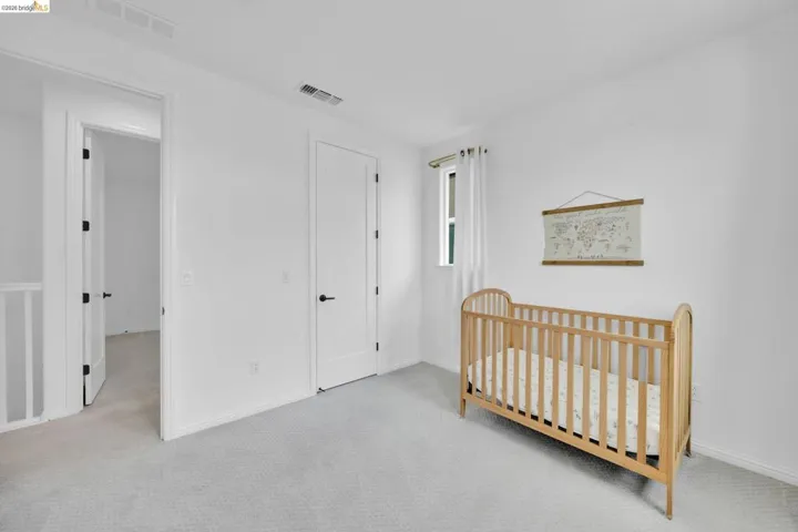 Carpeted room with white walls, a single window with white curtains, white trim, and matte black door hardware