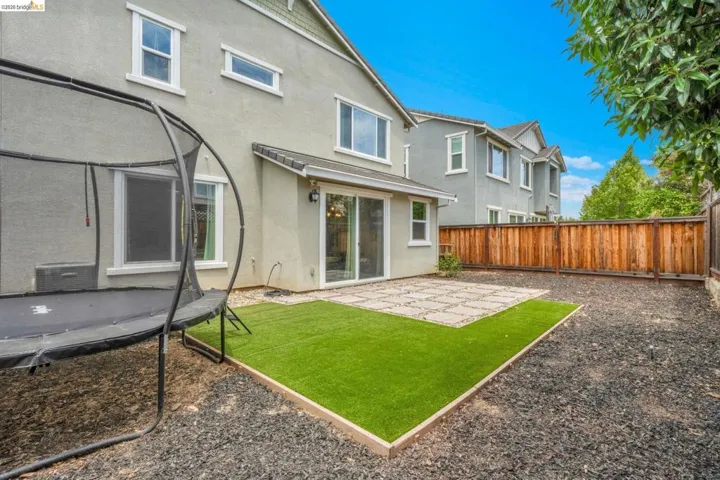 Private fenced backyard featuring a stone paver patio, artificial turf area, and dark gravel​​‌​​​​‌​​‌‌​​‌​​​‌‌​​​‌​​‌‌​​‌‌​​‌‌​​​​ landscaping