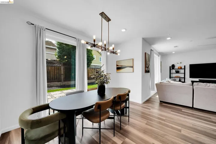 Dining area featuring wood-finish flooring, a contemporary chandelier, and a sliding glass door offering access to the outdoor space