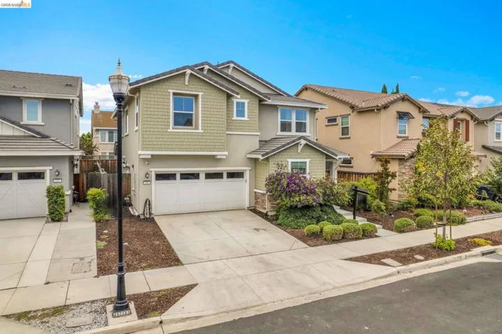 Two-story residence featuring a two-car garage, front landscaping, and a stucco and shingle exterior