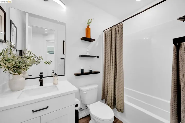 Bathroom featuring a white vanity with an integrated sink, matte black hardware, and a framed mirror