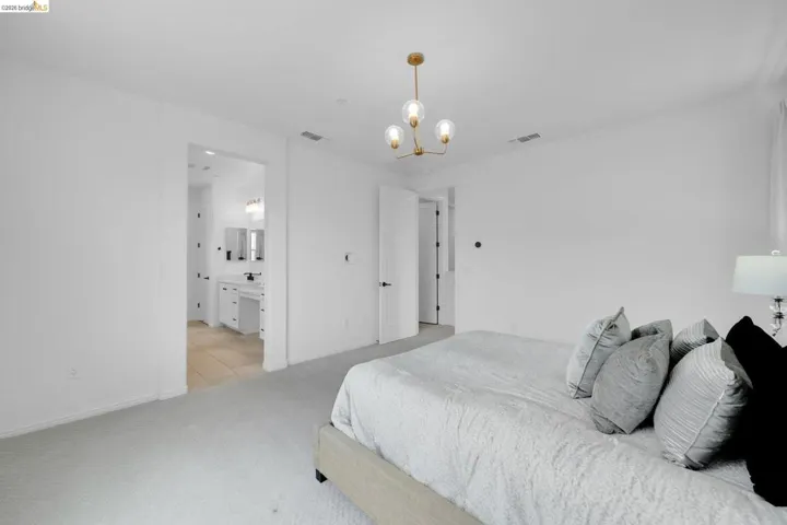 Open bedroom space with light-toned carpet flooring and white walls