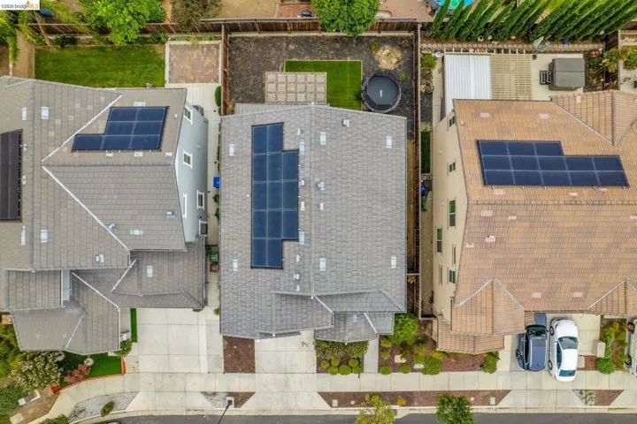 Aerial perspective showcasing a residential property with a shingle roof and integrated solar panel system