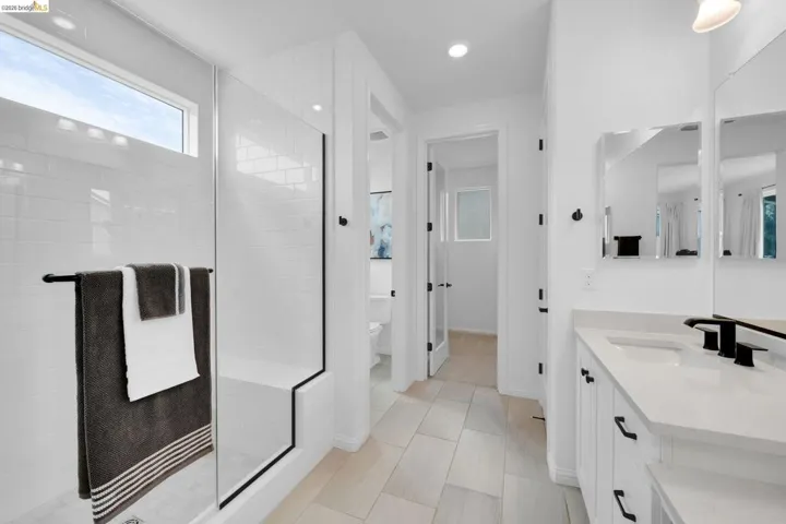 Modern bathroom featuring a glass-enclosed shower with white subway tile, a built-in bench, and a rectangular transom window
