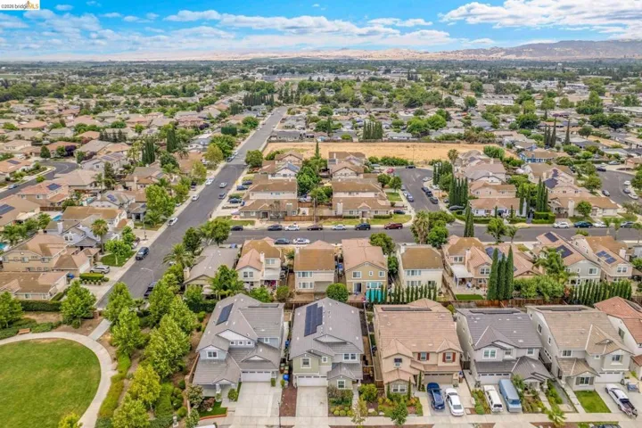 Residential neighborhood featuring a variety of single-family homes with diverse architectural styles, tree-lined streets, and a green space with walking paths
