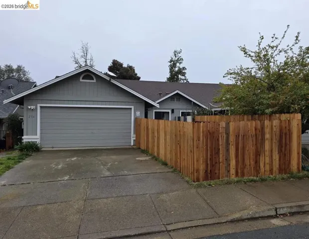 Front exterior featuring a two-car garage with a gray roll-up door, light gray siding, and a gabled roofline