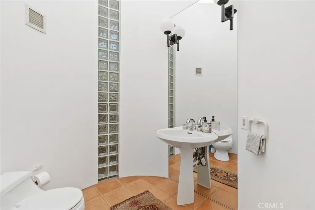 Half bath on top level off foyer entryway, has skylight in ceiling, glass block accents.