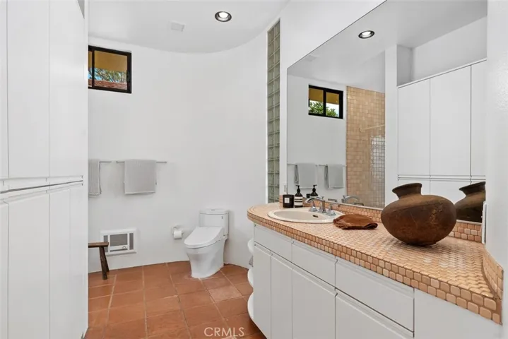 Primary bathroom is ensuite, has many cabinets for storage.