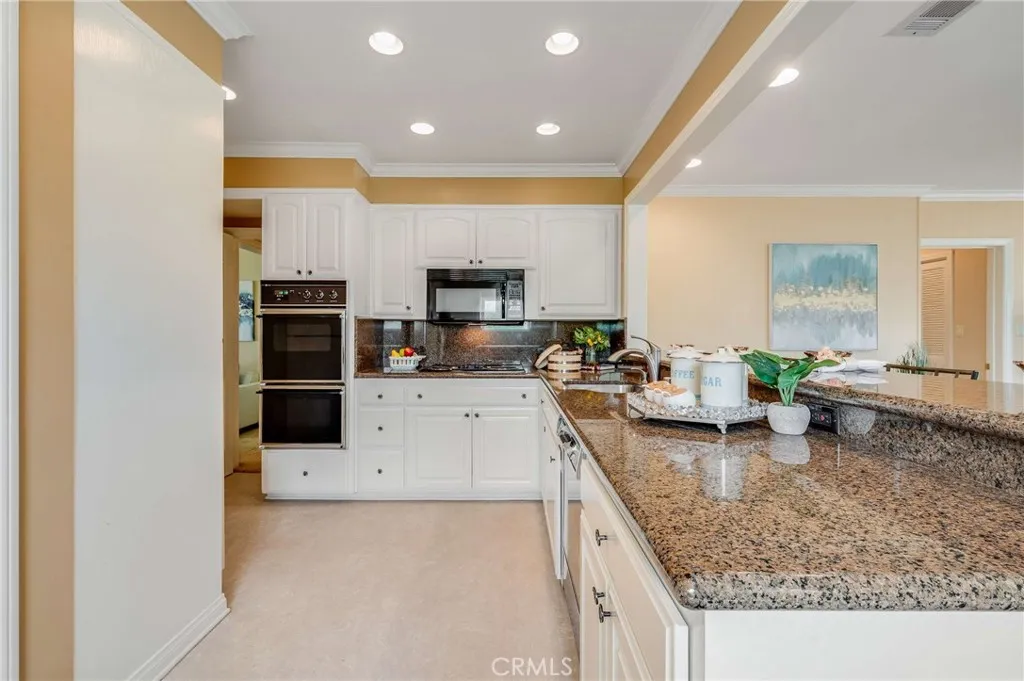 Updated kitchen with glossy white cabinets and granite countertops