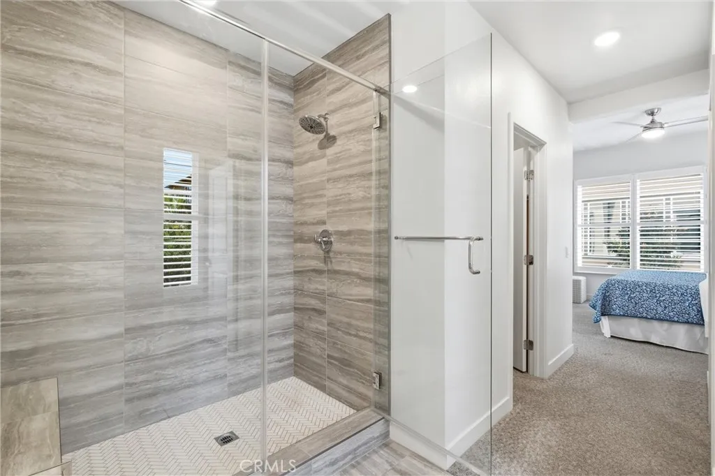 Oversized walk-in shower with floor-to-ceiling tile and frameless glass enclosure.