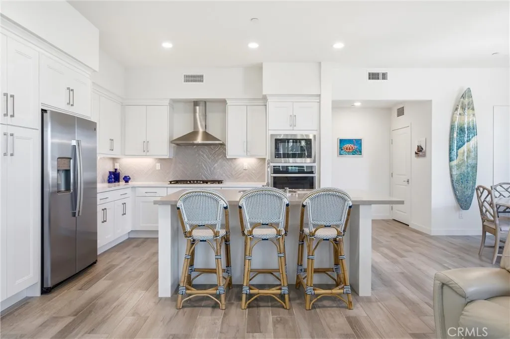 Chef-inspired kitchen with an oversized quartz island, shaker cabinetry, and stainless steel appliances.