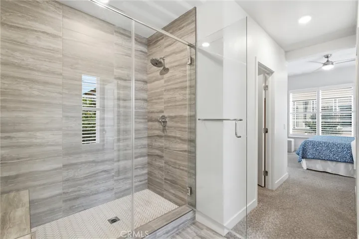 Oversized walk-in shower with floor-to-ceiling tile and frameless glass enclosure.