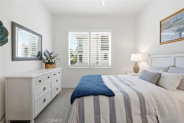 Bright guest bedroom with plantation shutters and coastal-inspired finishes.
