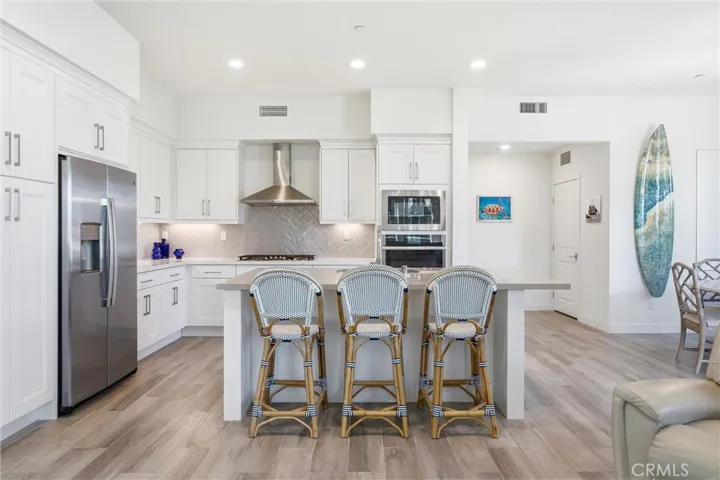 Chef-inspired kitchen with an oversized quartz island, shaker cabinetry, and stainless steel appliances.
