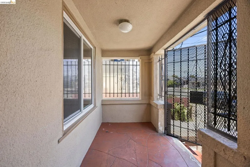 Covered porch entry featuring textured stucco walls and durable concrete flooring