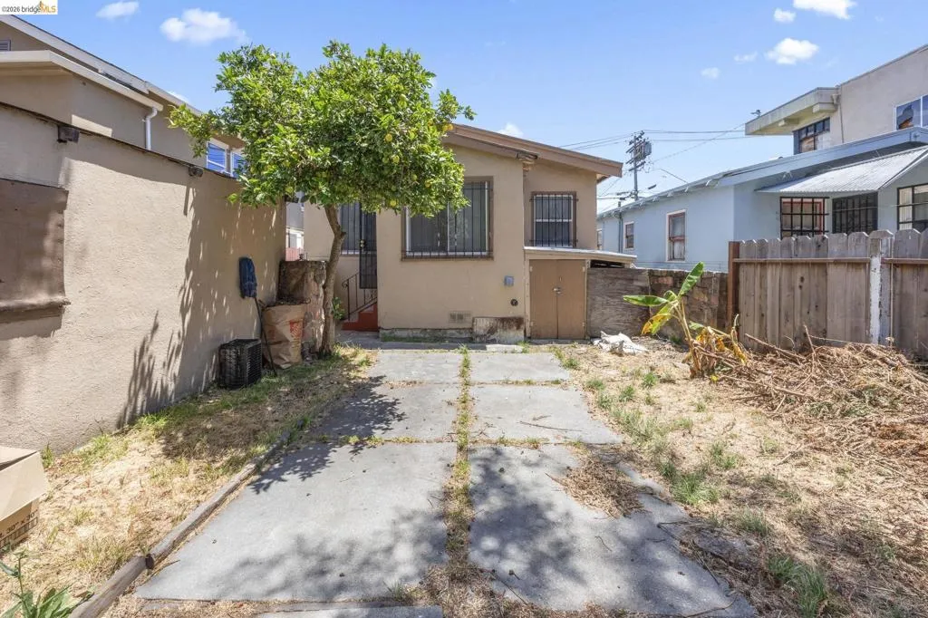 Rear exterior of the property featuring a concrete slab patio, stucco siding, and a wooden fence boundary