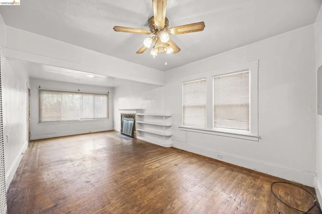 Living space featuring wood-finish flooring, a decorative fireplace, and built-in shelving