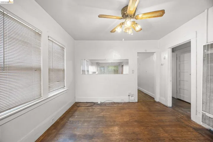 Room featuring wood-finish flooring, white walls, and multiple windows with blinds