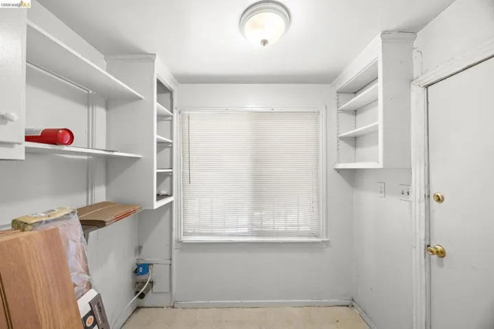 Room featuring a central window with blinds, overhead light fixture, and built-in shelving