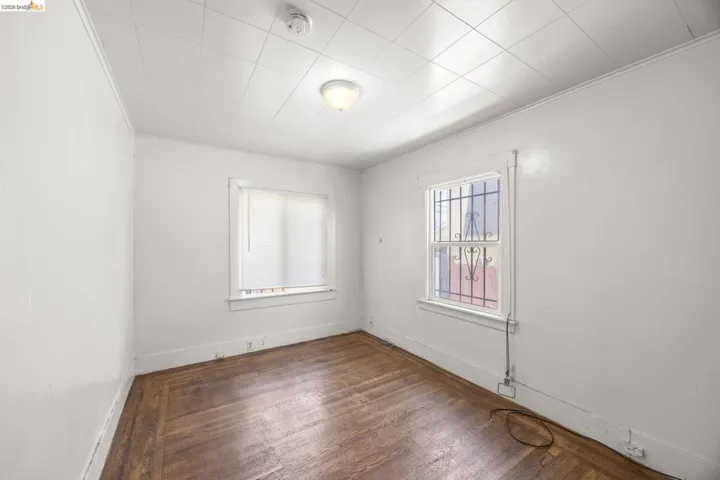 Room featuring wood-finish flooring, two windows providing natural illumination, and a ceiling-mounted light fixture