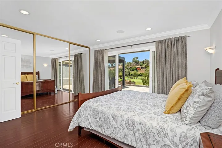 The spacious primary bedroom features mirrored wardrobe doors, bamboo flooring, and sliding doors opening directly to the patio and golf course beyond.